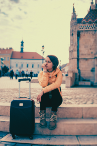 Woman sitting next to luggage in European city.